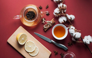 Close-up view of tea in glass pot, lemon, cotton flowers, cinnamon and lemon
