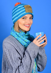 Fashion clothes. Autumn winter fashion. Smiling woman holds cup of hot drink. Isolated on blue background.