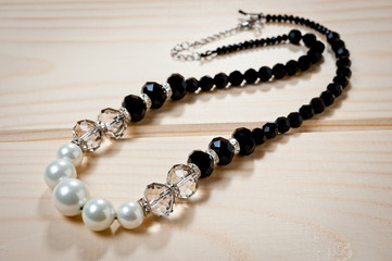 Beads of black and white pearls on a wooden background