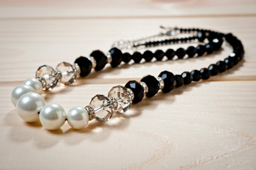 Beads of black and white pearls on a wooden background