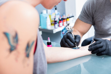 Close-up of the hands of a skilled tattoo artist wearing black gloves while setting a sterile machine for tattooing in a modern studio