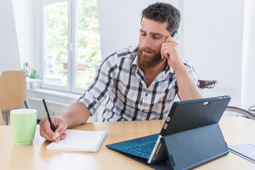 Close-up of the hand of a creative young man holding a pencil over a blank notebook, while thinking of a new project or assignment during freelance work in a co-working space