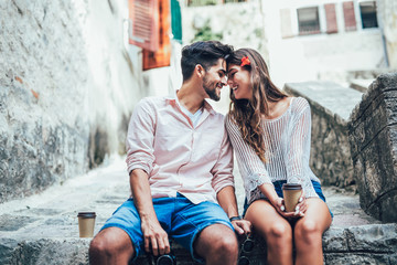 Romantic tourist couple sitting on stairs and drinking coffee