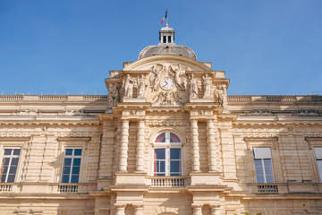 Luxembourg Gardens with yellow flowers, green grass, sculptures, chairs.