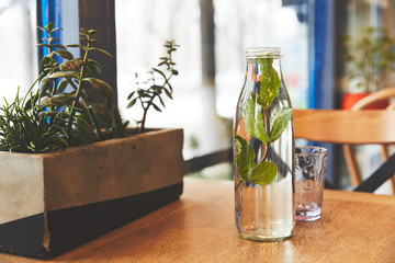 Bottle with mint water and glass on table