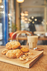 Homemade chocolate chip cookies on wooden table with flat white coffee