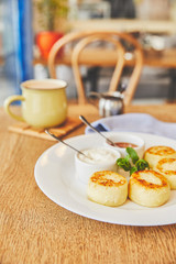 Cheese pancakes served with honey and sour cream on table with coffee