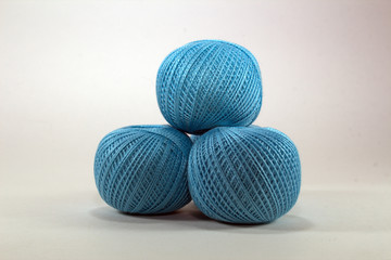 three blue skeins of natural cotton for needlework on white background close-up