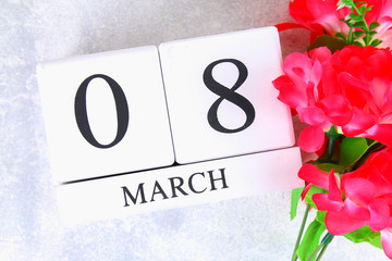 March 8, International Women's Day. Wooden perpetual calendar and pink flowers.