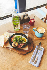 Brunch in restaurant with fried eggs served in pan and coffee