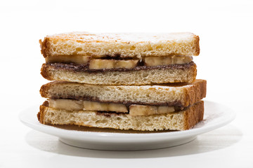 sweet sandwich with chocolate paste and banana on white plate