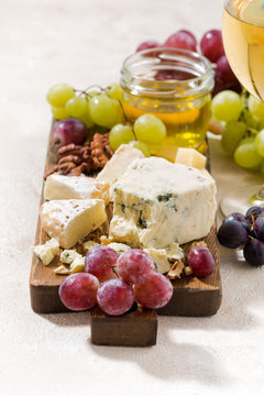 cheeseboard, grapes and wine on a white background, vertical