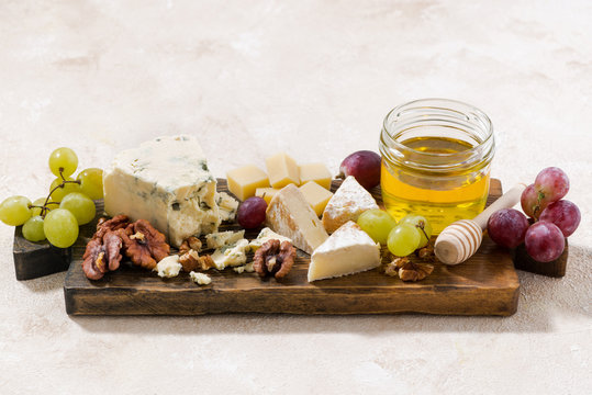 cheeseboard, grapes and honey on a white background, top view
