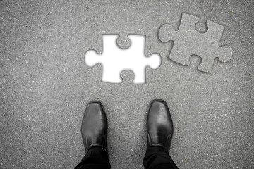 Business concept. Businessman standing on the road with missing piece of jigsaw puzzle
