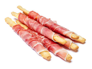 Bread sticks grissini with prosciutto isolated on white background
