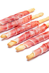 Bread sticks grissini with prosciutto isolated on white background