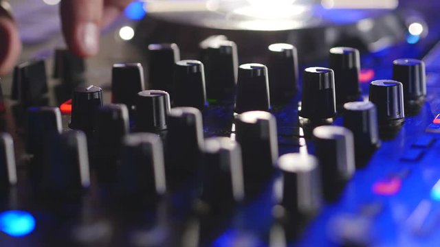 Man hands turning knobs on professional DJ mixer console