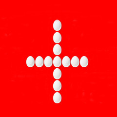 Switzerland  flag made from white Easter eggs on red background.