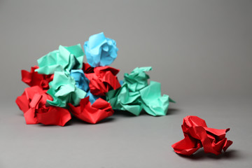 Crumpled paper ball near pile of different ones on grey background. Difference concept