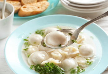 Spoon with tasty dumpling over plate