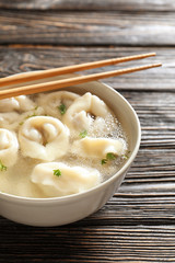 Tasty broth with dumplings on wooden table