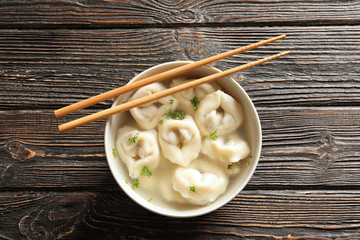 Tasty broth with dumplings on wooden table