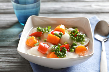 Tasty broth with dumplings on wooden table