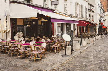 Fototapeta na wymiar Cozy street with tables of cafe in quarter Montmartre in Paris, France