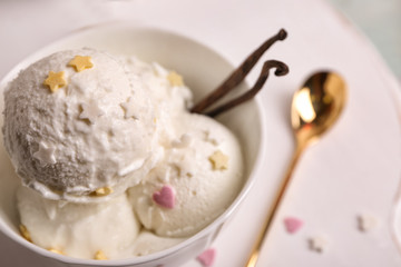 Cup with delicious vanilla ice cream on table, closeup