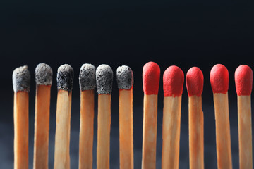 Group of burnt matches among others on black background. Difference and uniqueness concept