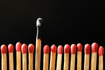 Burnt match among others on black background. Difference and uniqueness concept