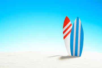 Two surfboards on a sandy beach