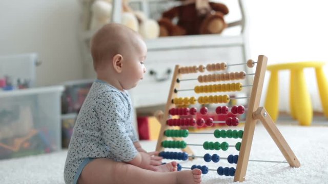 Cute little baby boy, playing with abacus at home, sunny kids room