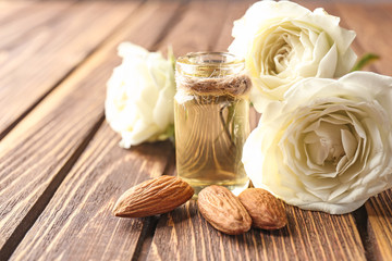 Bottle of perfume oil, almond and roses on table