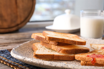 Plate with toasted bread on table