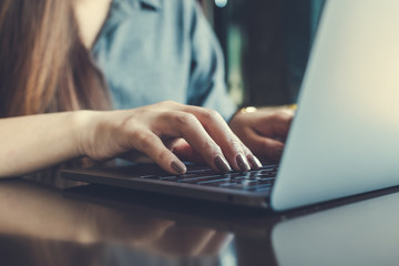 Closeup image of a business woman's hands working and typing on laptop keyboard on the table