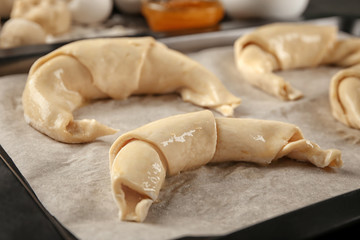 Uncooked croissants on baking sheet, closeup