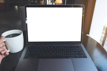Fototapeta premium Mockup image of a businessman using laptop with blank white desktop screen while drinking hot coffee in cafe