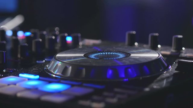 DJ turning knobs on professional mixer console and playing music in nightclub