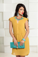 Beautiful Woman in Yellow Dress and Trendy Blue Accessories on White Studio Background