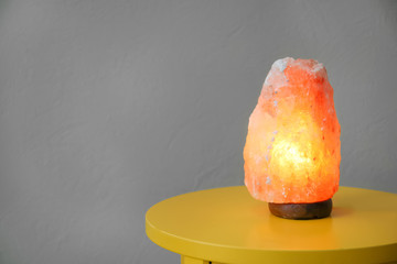 Himalayan salt lamp on table against color background