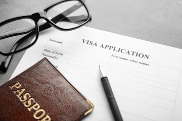 Passport, glasses and visa application form on table. Immigration reform