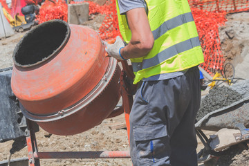 Construction worker on a cement / concrete mixer doing hard job.