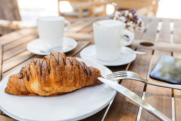Coffee cup and fresh baked croissants on wooden background. Top View.