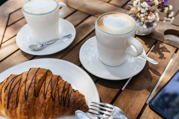 Coffee cup and fresh baked croissants on wooden background. Top View.