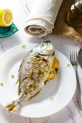 Dorada baked and stuffed with lemon on a white plate