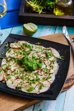 Carpaccio of an octopus on a square black plate. Italian Cuisine