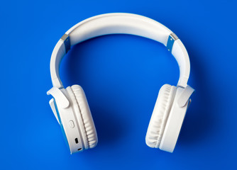white wireless bluetooth earphones on blue background