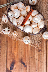 Raw fresh mushrooms in a metal basket on a wooden table, top view, copy space
