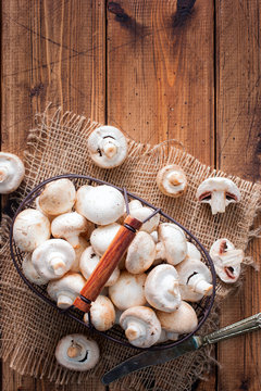 Raw fresh mushrooms in a metal basket on a wooden table, top view, copy space